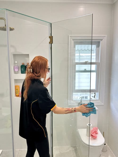 professional cleaner cleaning shower glass