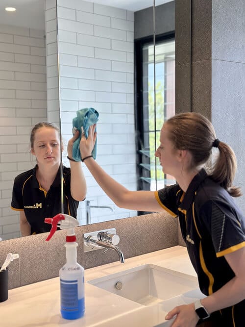 professional cleaner cleaning the bathroom mirror