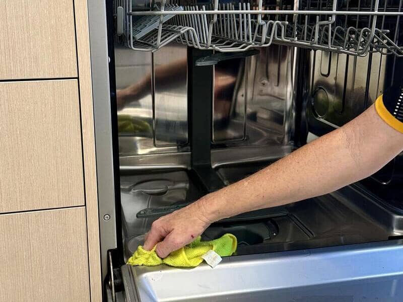 professional cleaner wiping the inside of a dishwasher