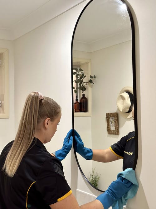 professional cleaner wiping the frame of the mirror with cloth