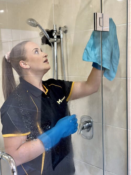 professional wiping the crevices and corners of shower glass