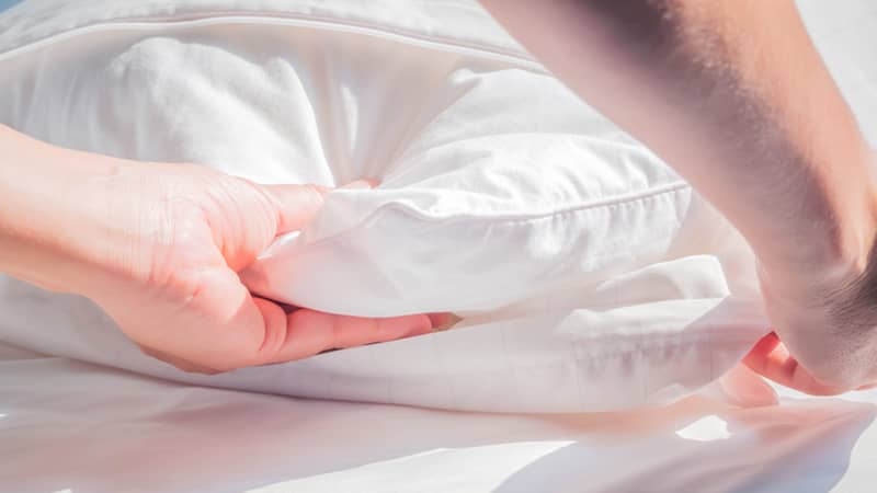 female hands removing cover from a white pillow