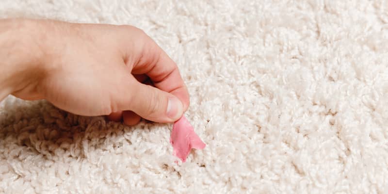 woman hand removing gum from carpet by hand