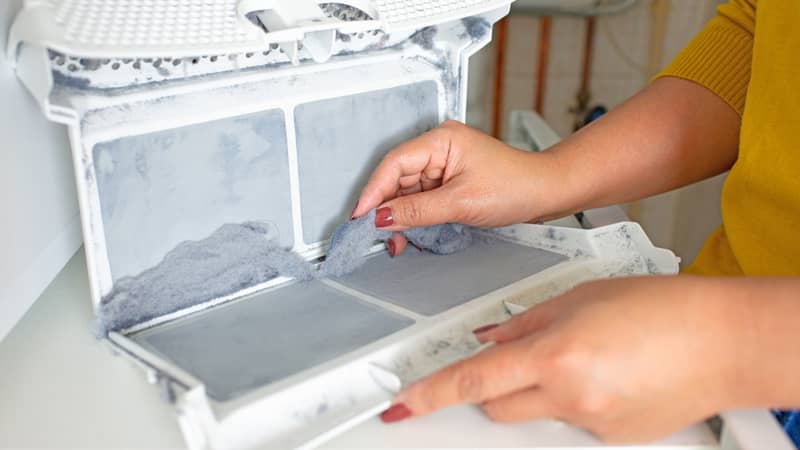 Woman cleanup lints and dirt from tumble dryer filter. 