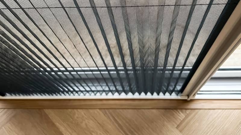 Selective focus mosquito net wire screen on door near wooden floor.