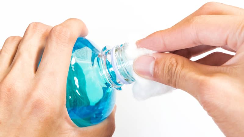 man holding ethyl alcohol bottle and cotton ball