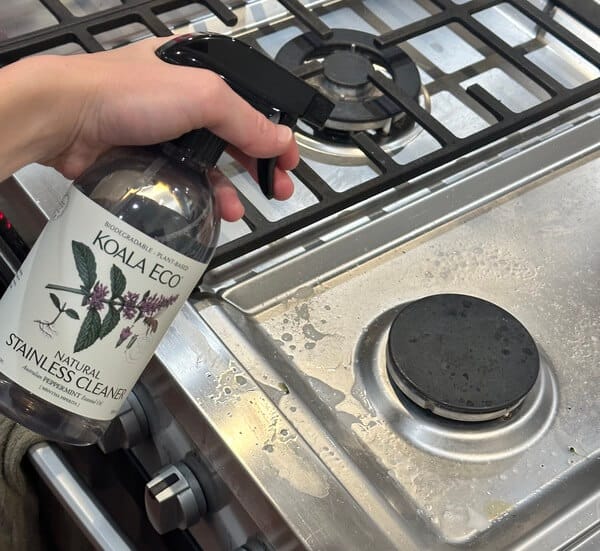 spraying Koala Eco Stainless Steel Cleaner on stove top