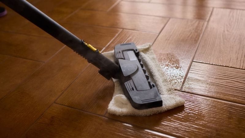 cleaning brown-tiled floor with steam mop