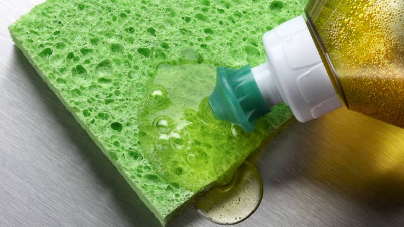 macro shot of dish soap being squeezed onto green sponge