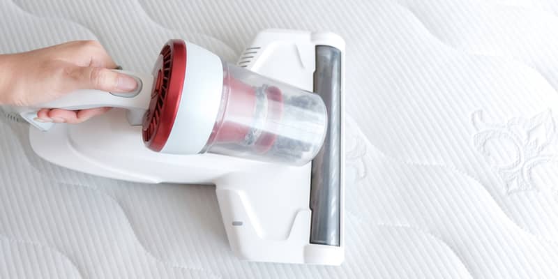 hand cleaning the mattress using a vacuum