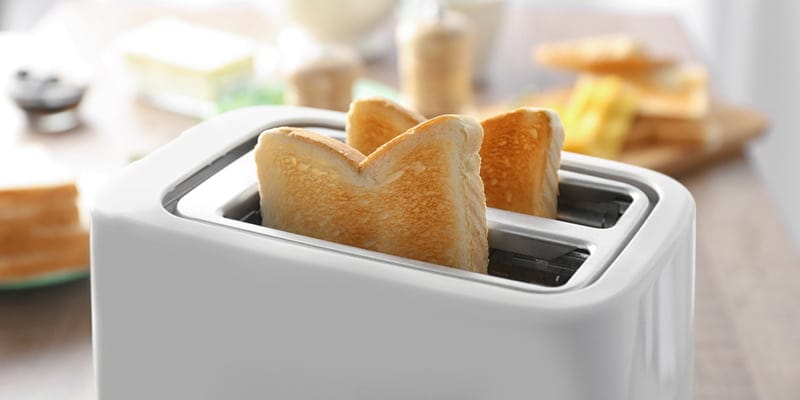 Toaster with tasty breakfast toasts on table