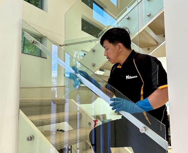 Ugyen cleaning the handrail of a glass staircase