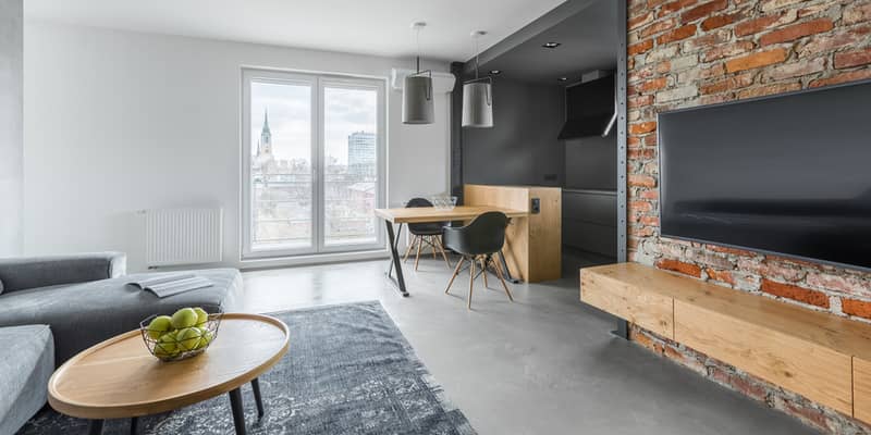 Open plan studio with tv screen on exposed brick wall