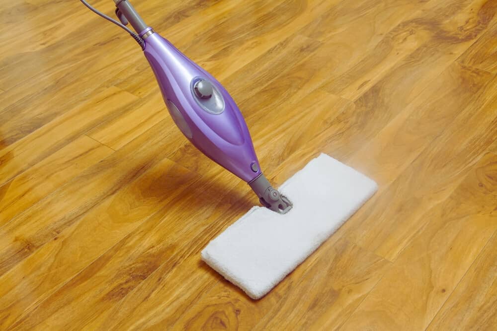 Using a purple steam mop to clean wooden floor