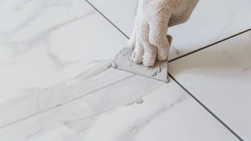 Grouting tiles seams with a rubber trowe