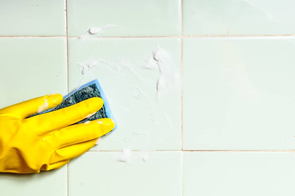 hand cleaning tiled surface in bathroom or kitchen