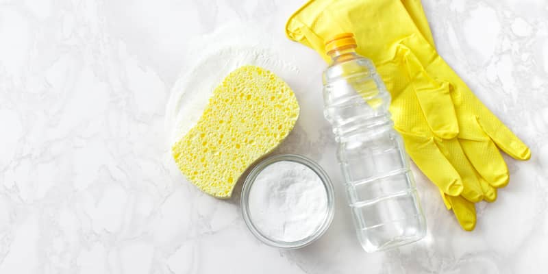 cleaning supplies - baking soda, sponge, vinegar in a bottle, gloves