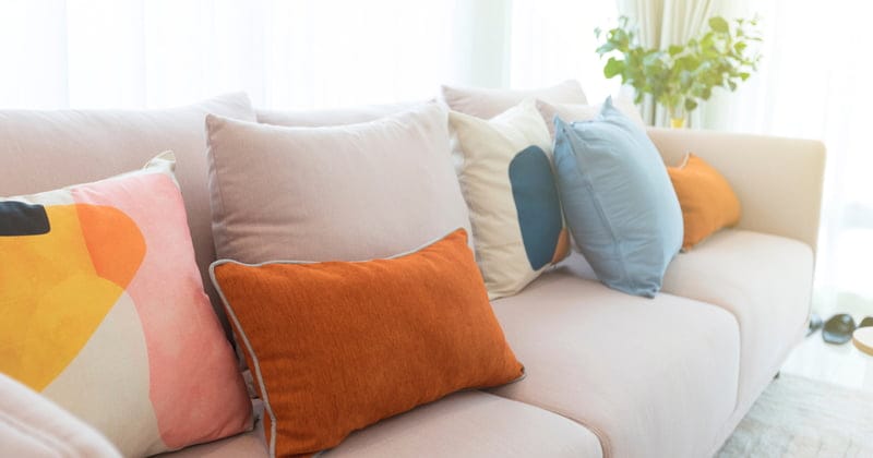 Cozy white sofa with colorful suede pillows in modern living room.