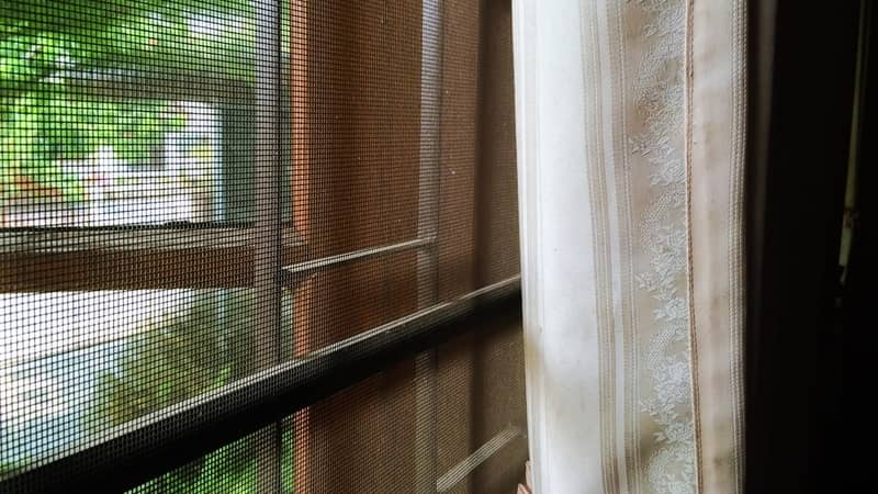 abstract close up part of wooden window and curtain with mosquito wire screen and Curved steel in house