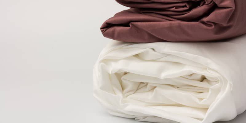 Stack of folded clean white and maroon bed sheets