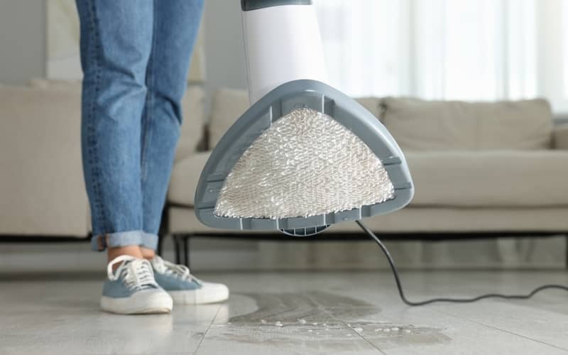 person cleaning the floor with a steam mop at home