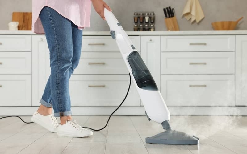 person cleaning the floor with steam mop in kitchen