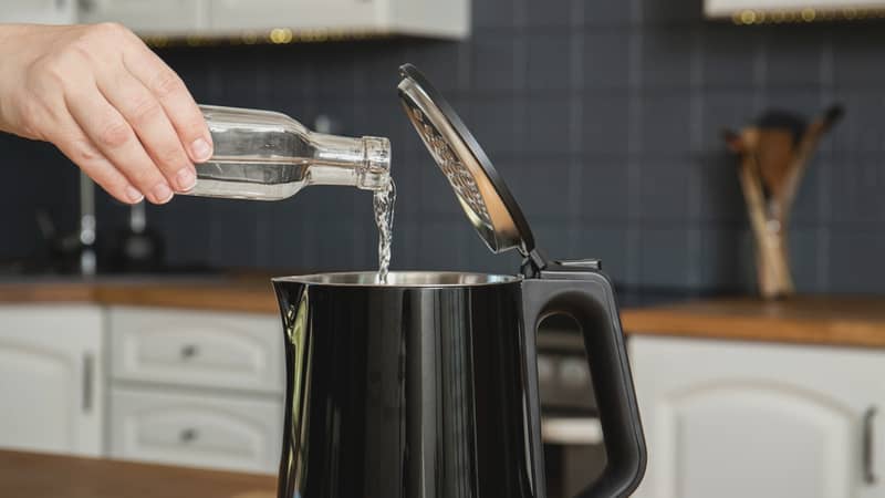 woman hand pouring vinegar inside the kettle for descaling