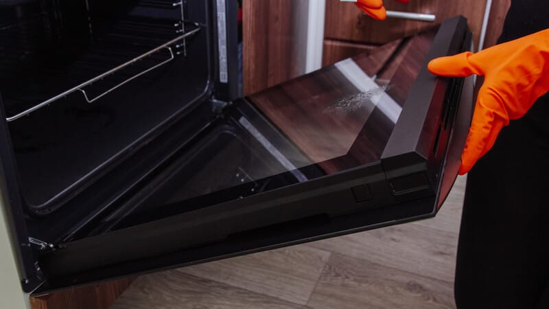 woman hands with gloves opening the oven door