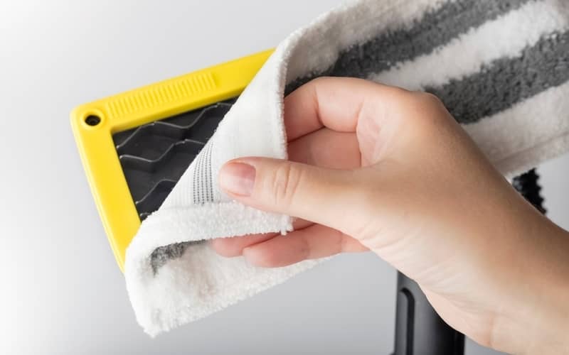 person attaching or removing a cleaning pad to a steam mop head